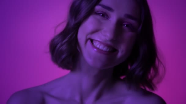 Closeup shoot of young pretty girl laughing happily in front of the camera with neon blue background — Stock Video