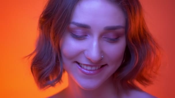 Closeup shoot of young attractive caucasian female being cute and smiling happily looking at camera with neon red background — Stock Video