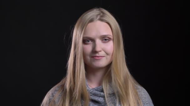 Retrato de jovem loira modelo de cabelos lisos posando sorrindo para a câmera no fundo preto . — Vídeo de Stock