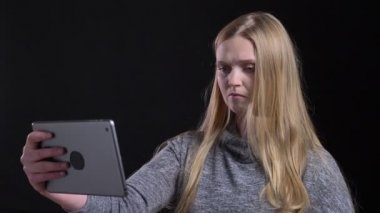Siyah arka planda tablet kullanarak mütevazı videochat konuşurken sarışın düz saçlı kız portre.