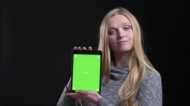 Siyah arka planda uygulamayı tavsiye etmek için tablet yeşil ekran gösteren sarışın düz saçlı uzman portresi.