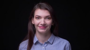 Siyah arka planda kamera içine mütevazı ve sevinçle gülümseyen mavi bluz genç esmer işkadını portre.