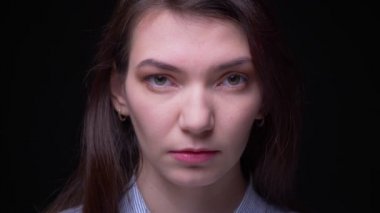 Konsantre esmer iş kadını yakından kamera siyah arka planda ciddi ve sabitten izlerken portre.