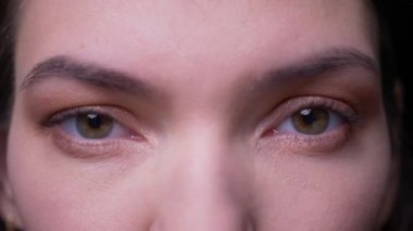 Sessiz esmer işkadını siyah arka planda kamera içine ciddiye izlerken yakın çekim göz-portre.