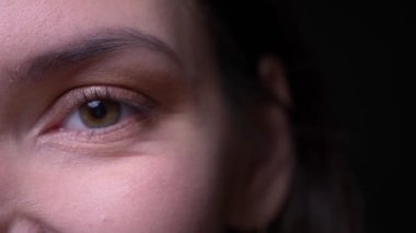 Sakin esmer iş kadını siyah arka planda sevinçle kamera içine izlerken yakın çekim bir göz portresi.