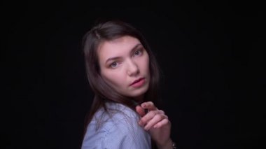 Mavi bluz değişen genç esmer işkadını portre siyah arka planda kamera içine moda pozlar.