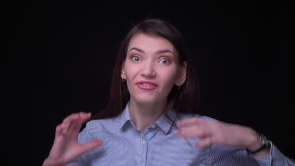Porträt einer jungen brünetten Geschäftsfrau in blauer Bluse, die vor schwarzem Hintergrund freudigen Schock und Überraschung in die Kamera zeigt. — Stockvideo