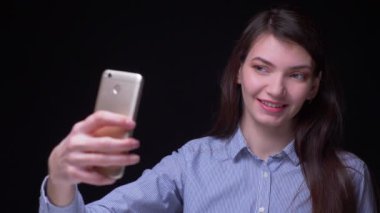 Siyah arka planda mutlu olan akıllı telefon kullanarak selfie-fotoğraf yapma mavi bluz güzel esmer işkadını.