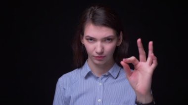 Güzel esmer işkadını mavi bluz işaret ok işareti her şeyi göstermek için serin ve siyah arka planda kamera ile flört.