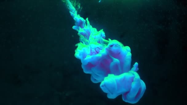 Tinta de pintura de color azul cae en el agua en cámara lenta sobre fondo negro con nube de tinta girando y explosión de humo abstracto . — Vídeo de stock