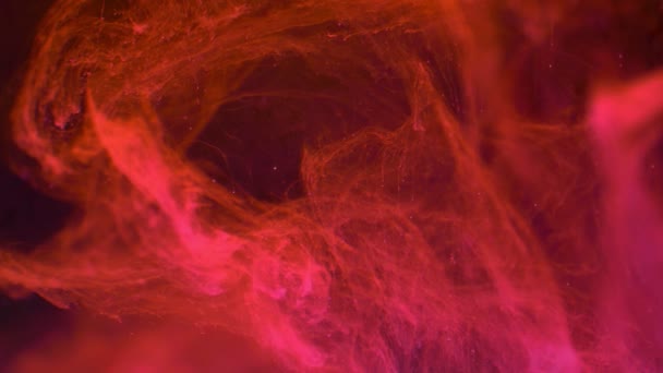 L'encre de peinture de couleur rouge diffuse dans l'eau au ralenti sur fond noir avec un nuage encré circulant et une explosion de fumée abstraite .