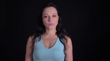 Siyah arka planda kamera ciddiye izlerken Orta yaşlı güzel uzun saçlı kadın portre.