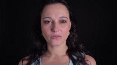 Orta yaşlı güzel uzun saçlı kadının siyah arka planda kamera içine dikkatle izlerken yakın çekim portre.