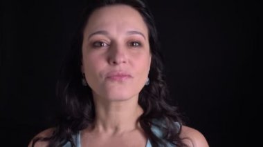 Orta yaşlı güzel uzun saçlı kadının yakın çekim portresi, siyah arka planda kameraya uyarak.