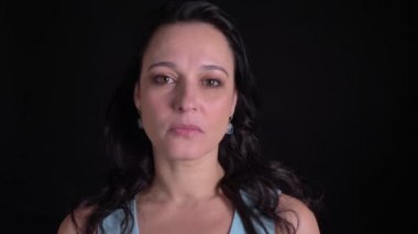 Siyah arka planda kameraya mutlu gülümseme ile izlerken Orta yaşlı kadının portresi.