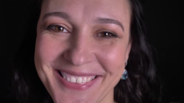 Blízký portrét ženy středního věku, která pozoruje s mimořádně šťastným úsměvem na černém pozadí. — Stock video