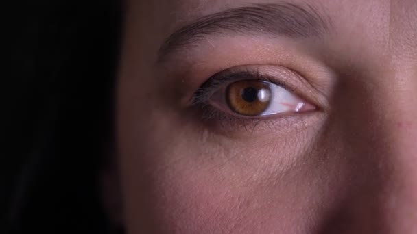Close-up eye-portrait of middle-aged woman watching smilingly into camera on black background. — Stock Video