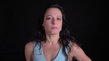 Orta yaşlı güzel uzun saçlı kadının portresi, siyah arka planda kamera içine olumlu şekilde sallıyor.