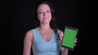Siyah arka planda uygulamayı tavsiye etmek için tablet yeşil ekran gösteren orta yaşlı kadının portresi.