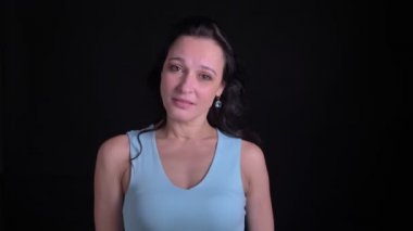 Siyah arka planda olumlu umut göstermek için çapraz parmaklar işareti gösteren orta yaşlı kadının portresi.