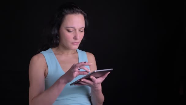 Portret van middelbare leeftijd vrouw kijken met grote belangstelling en verrassing in Tablet op zwarte achtergrond. — Stockvideo