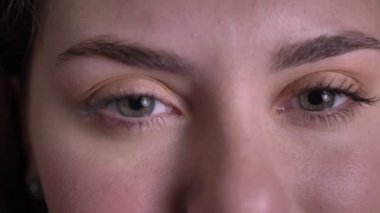 Güzel sarışın kadının yakın yukarı göz portre gözleri açar ve siyah arka planda kamera içine gülümseyerek izliyor.
