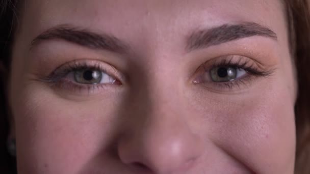 Close-up eye-portrait de bela mulher loira assistindo sorridente na câmera e piscando no fundo preto . — Vídeo de Stock