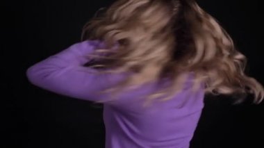 Sevimli sarışın beyaz kadın etrafında Spinning ve siyah arka planda mutlu saç sallayarak portresi.