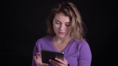 Siyah arka planda tür gülümseme ile kamera içine tablet saatler ile çalışan mutlu kadının portresi.