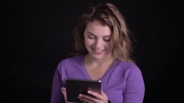 Siyah arka planda sevinçle tablet ile çalışan kadın portresi.