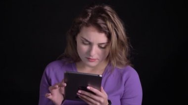Siyah arka planda şaşkınlık ile tablet çalışan kadın portresi.
