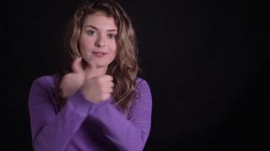 Siyah arka planda gibi ve saygı göstermek için kameraya memnuniyetle parmak işaretleri işaret sevimli kadın portre.
