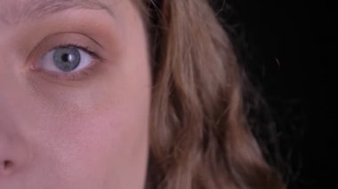 Genç kıvırcık saçlı kız yakın yukarı yarı portre siyah arka planda mesafe dikkatlice izliyor.