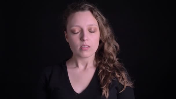 Portrait of young curly-haired girl shows extreme happiness and raises hands in gladness into camera on black background. — Stock Video