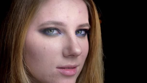 Primer plano de brote de joven hermosa cara femenina con hermoso maquillaje con fondo aislado en negro — Vídeo de stock