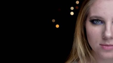 Arka planda bokeh ışıkları ile kamera sevimli makyaj bakarak gözleri ile genç güzel kadın yüzü closeup yarı yüz çekimi