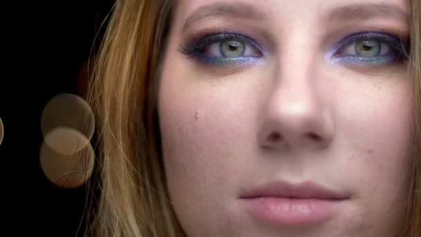 Close-up tiro de jovem bela cara feminina com olhos olhando para câmera bonito maquiagem com fundo bokeh — Vídeo de Stock