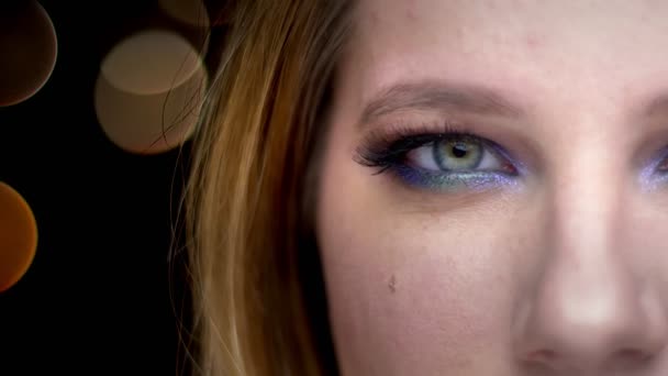 Closeup, napůl tvář, krásná ženská tvář s očima, které se dívají na kameru s úsměvem na pozadí — Stock video