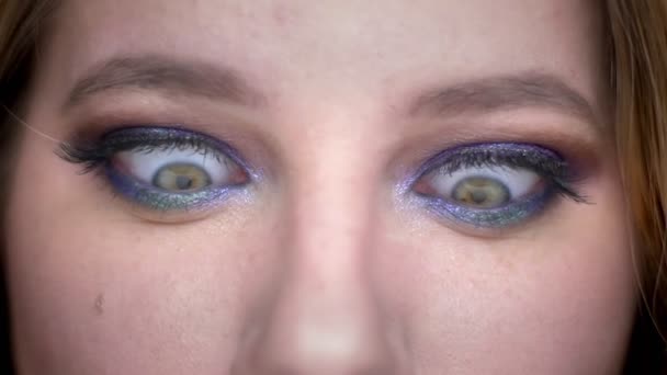 Close-up shoot van jonge mooie vrouwelijke gezicht met ogen kijken naar camera met gekke gezichtsuitdrukking met mooie make-up toegepast — Stockvideo