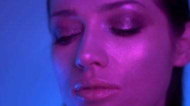 Renkli mor ve mavi neon ışıklar fütüristik moda modeli sola izlerken stüdyoda kameraya poz.