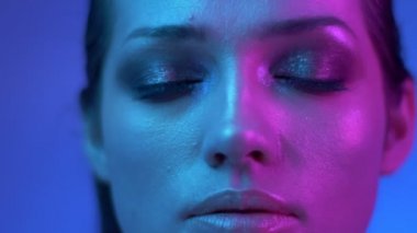 Renkli neon ışıklar glitter makyaj ile Fütüristik moda modeli dikkatle izliyor ve stüdyoda gözlerini kapatarak.