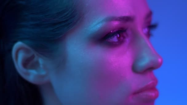 Modèle de mode lumineux de profil dans des néons violets et bleus colorés regardant vers la droite en studio . — Video