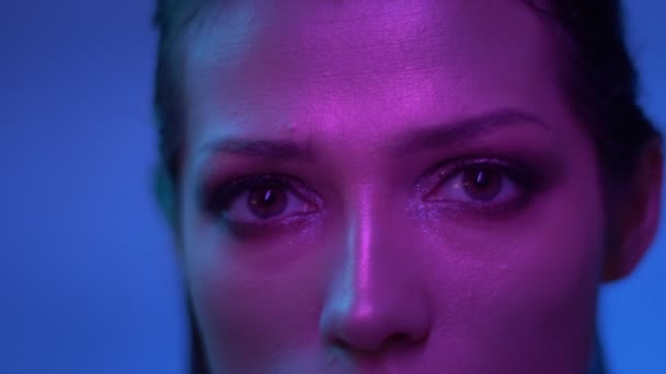 Fantastische mode model met glitter make-up in paarse neonlichten kijken met minachting in de camera in Studio. — Stockvideo
