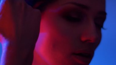 Kırmızı neon ışıklar glitter göz gölgeleri ile fantastik moda modeli nin yakın çekim yüzüne şefkatle dokunmadan.