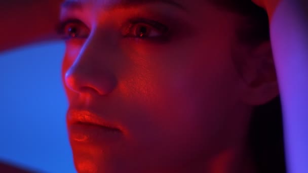 Närbild shoot av Fantastic Fashion modell med glitter ögonskuggor i röda neonljus kör händerna genom hennes hår. — Stockvideo