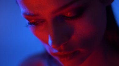 Kırmızı neon ışıklar glitter göz gölgeleri ile fantastik moda modeli yakın çekim ciddi aşağı saatler.