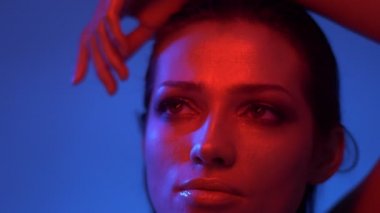 Fütüristik moda modeli kırmızı ve mavi neon ışıklar ve yukarı pensively ve kamera içine bakarak.