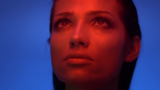 Närbild shoot av mode modell i rött och blått neonljus titta uppåt och stänga ögonen i tillfredsställelse. — Stockvideo