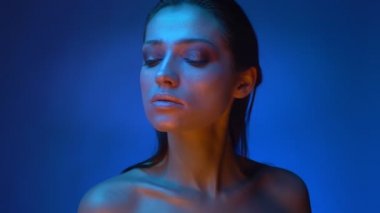 Mavi neon ışıklar parlayan moda modeli gururla aşağı baskın olma izliyor.