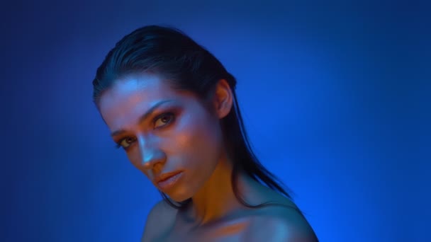Glowing fashion model in blue neon lights watching dreamily upwards being concentrated and inspired. — Stock Video